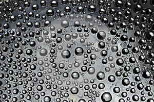 Silver drops flow down on the gray mirror ice surface. Close-up.