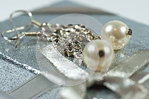 Silver earrings with gems and pearls on shiny gift box