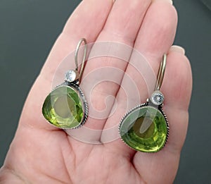 Silver earrings with green stones at hand. Indian ethnic style