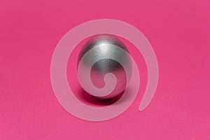 Silver egg on a dark pink background. Abstract Easter background