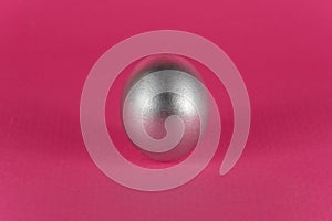 Silver egg on a dark pink background. Abstract Easter background