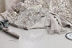 Silver fabric with paillettes, beads and scissors on white table
