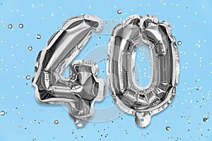 Silver foil balloon number, digit forty on a blue background with sequins. Birthday greeting card with inscription 40.