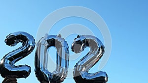 Silver foil number 2023 change to 2024 celebration new year balloon on blue sky background. Happy New year greetings