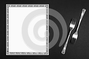 Silver forks and empty menu on background, flat lay. Space for text