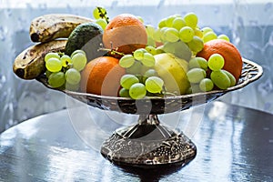 Silver fruit bowl by the window.