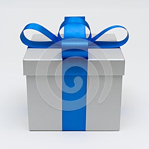 Silver gift box with blue satin bow ribbon on white background