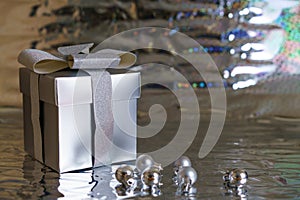 Silver gift box with christmas balls on shiny background