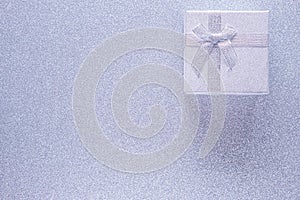 Silver gift box on glitter silver background with copy space. Top view. Xmas, Valentines day or birthday party concept. Greeting