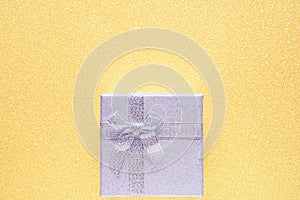 Silver gift box on glitter yellow background with copy space. Top view