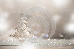 Silver glitter Christmas tree on grey background with lights bokeh, copy space. Greeting card for new year party. Festive holiday