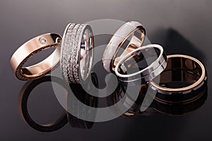 Silver, gold, platinum rings of different styles on the dark background of reflections