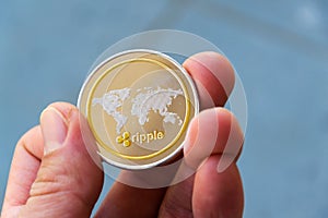 Silver gold ripple coin in hand, cryptocurrency investing concept