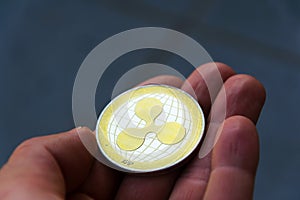 Silver gold ripple coin in hand, cryptocurrency investing concept