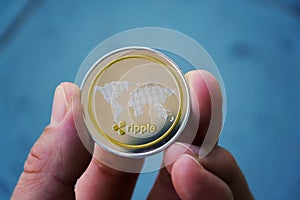 Silver gold ripple coin in hand, cryptocurrency investing concept