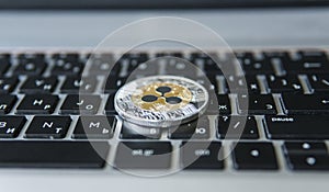 Silver gold ripple coin on a laptop keyboard closeup. Blockchain mining. Digital money and virtual cryptocurrency