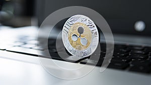 Silver gold ripple coin on a laptop keyboard closeup. Blockchain mining. Digital money and virtual cryptocurrency