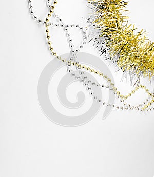 Silver and golden chain with balls, beads, yellow tinsel in right corner. New year decorations on a white background. Christmas co