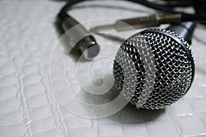 Silver Grille microphone with XLR cable on white leather SELECTIVE FOCUS