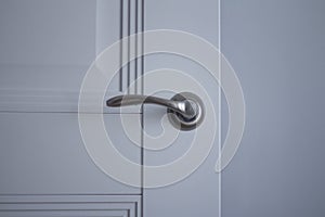 The silver handle on a white door