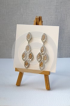 Silver handmade earrings on tinsel on grey textured fabric background