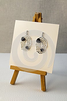 Silver handmade earrings on tinsel on grey textured fabric background