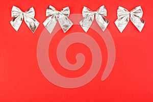 Silver holiday bows on a red background.
