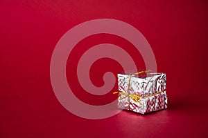 Silver holiday gift box on a red background. Copy space