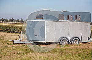 silver horse trailer on green weadow . A trailer used for transporting one adult horse A trailer used for transporting