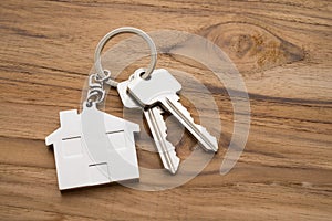 Silver house key with house keychain on wooden background with copy space. Dream new house buying, real estate property business