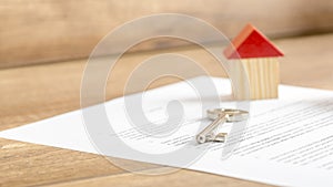 Silver house key lying on a contract of house sale