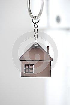 Silver house key in white door, with little keychain house, opening door to new house, home, investment, real estate concept,