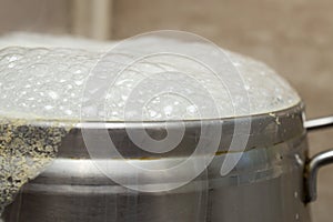 silver inox pot boiling over with white bubbles photo