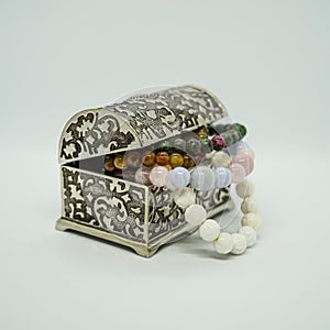 Silver jewelry box with beads on a white background.