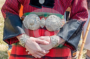 Silver jewelry. Traditional women`s clothing. A young woman in Bulgarian folk costume. Silver ornaments, red robe and silver belt