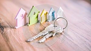 Silver Keychain in front of colourful miniature symbol of houses laying on the wooden surface