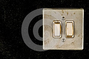 A silver light switch with two white buttons