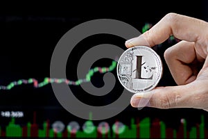 Silver Litecoin LTC cryptocurrency coin with candle graph background, Crypto is Digital Money within the blockchain network, is