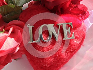 silver LOVE word, on red pillow heart, red roses. VALENTINES