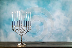 A silver menorah for the Jewish holiday Hanukkah with burning glowing eight candles