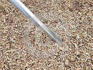 Silver metal bar or rod in brown mulch