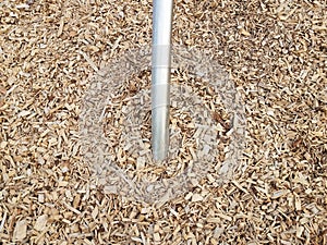 Silver metal bar or rod in brown mulch