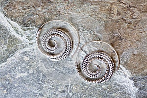 metal decorative oriental spirale design earrings on natural neutral background photo