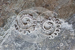 metal decorative oriental spirale design earrings on natural neutral background photo