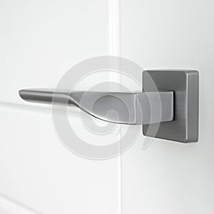 The silver metal doorknob is mounted in a white wooden door