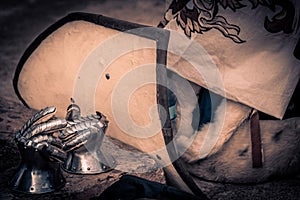 Silver metal gauntlets beside a shield before entering to battle