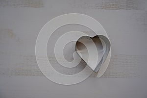 Silver metal heart-shaped biscuit cutter for baking on a wooden background top view. Copy space