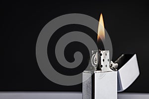 Silver metal lighter with flame on black background , classic lighter