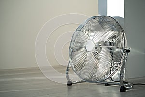 Silver metal ventilation fan on wooden floor at home