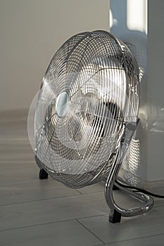 Silver metal ventilation fan on wooden floor at home